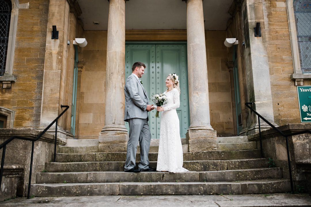 bride and groom stood on large stone steps smiling
