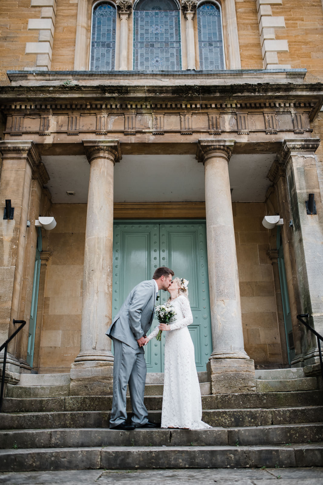 bride and groom stood kissing on large stone stairway