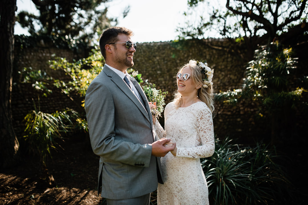 bride in white dress waring sun glasses laughing in garden