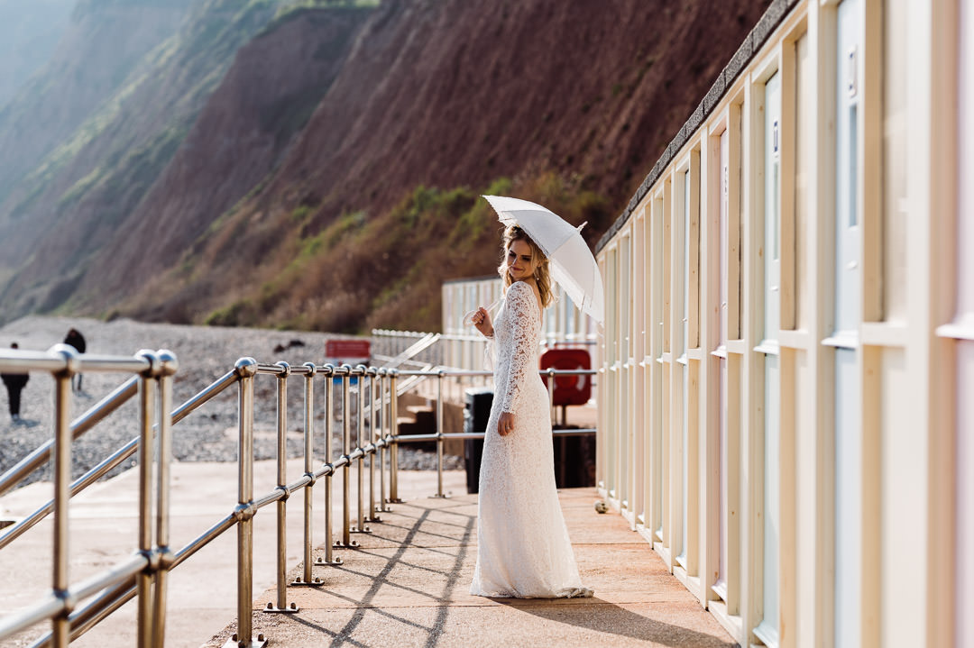 bride stood near beach huts in the sunlight