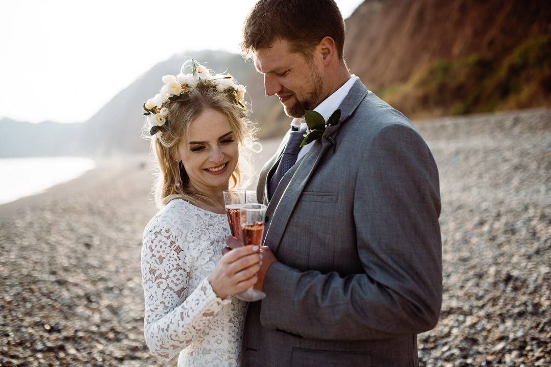 bride and groom drinking champagne on beach