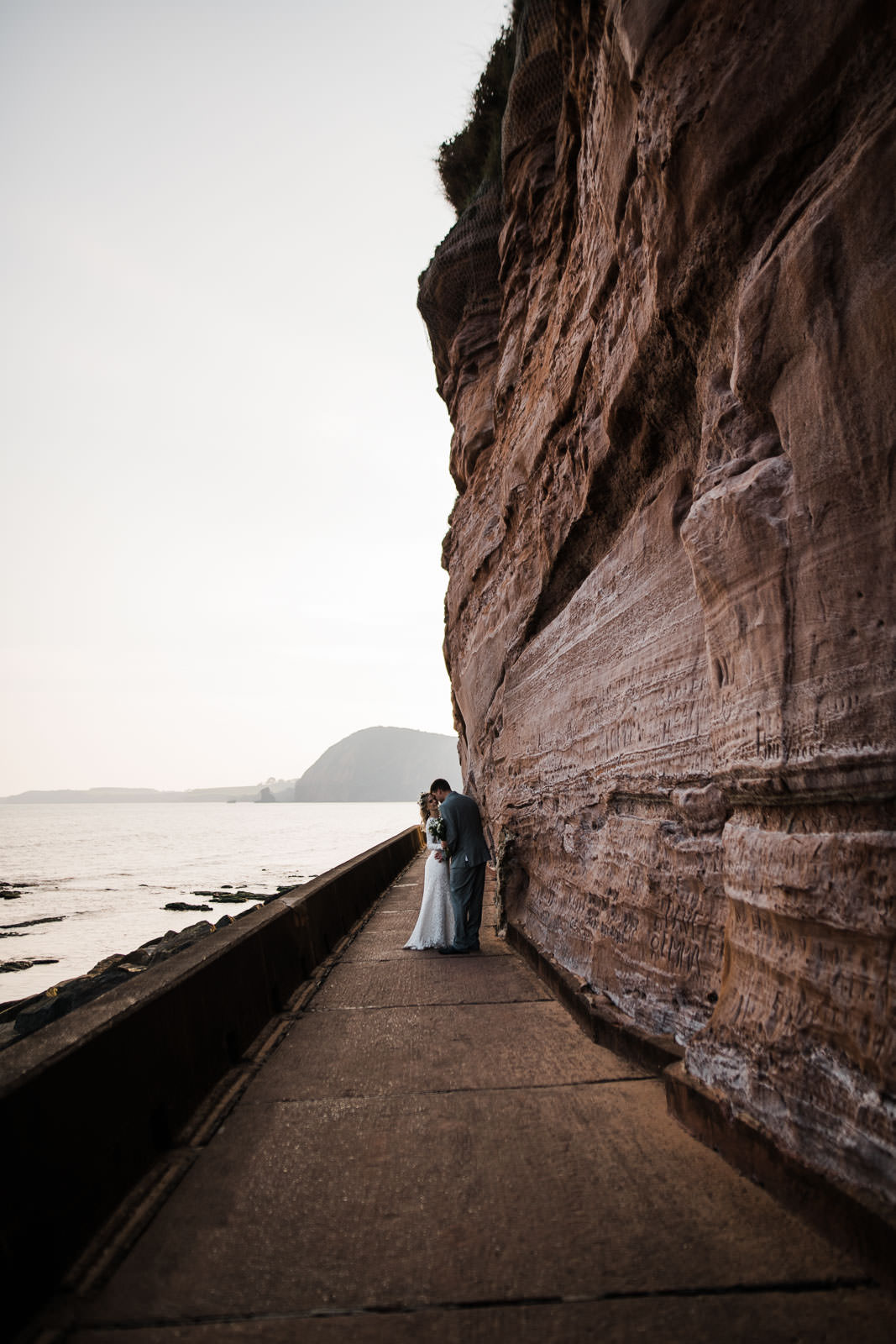 bride and groom stood at bottom of red cliff formation