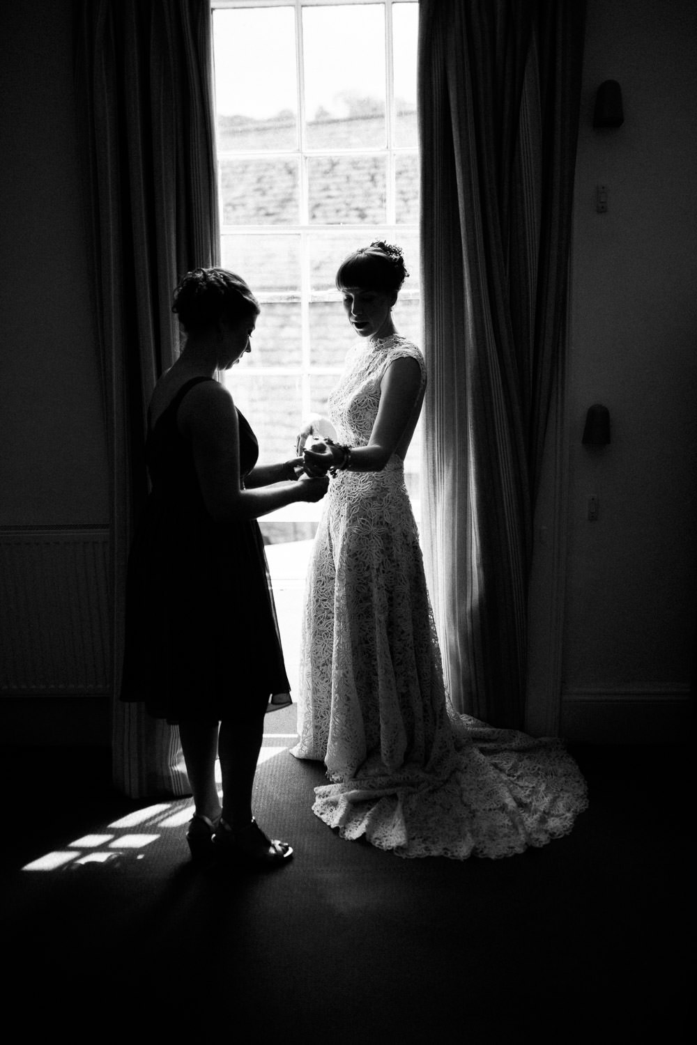 bride in white dress stood in window light