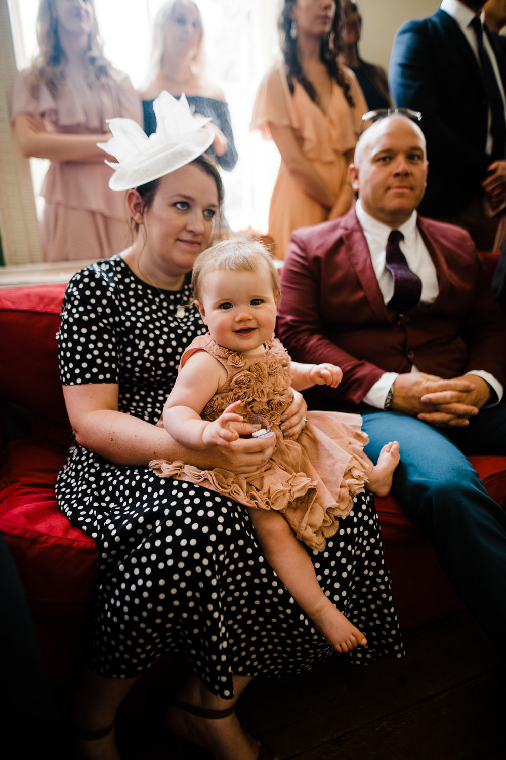 baby smiling at wedding sat on woman's lap