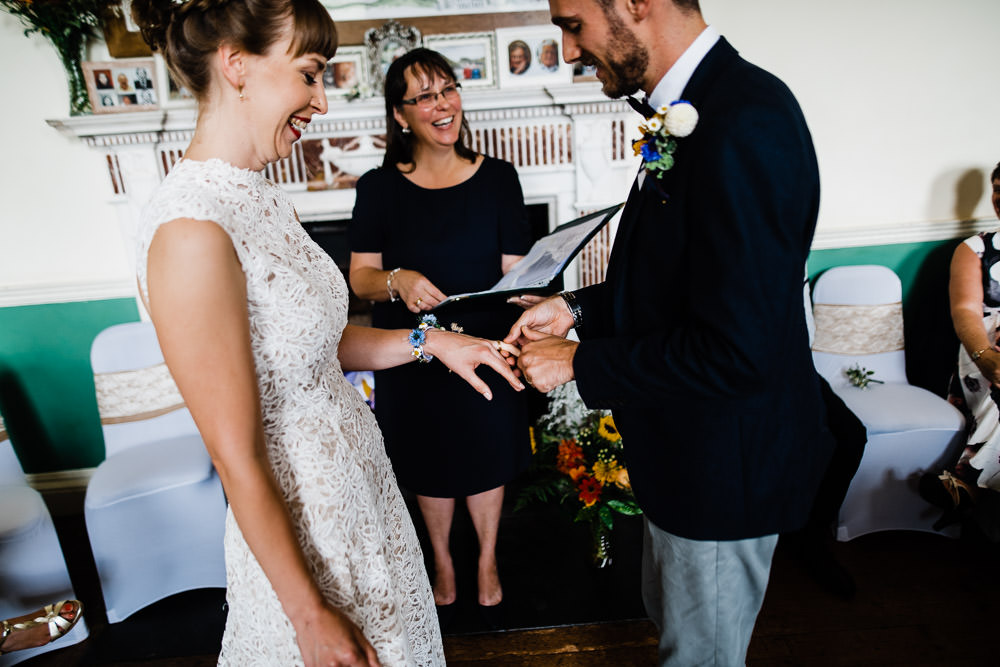groom putting ring on brides finger at wedding
