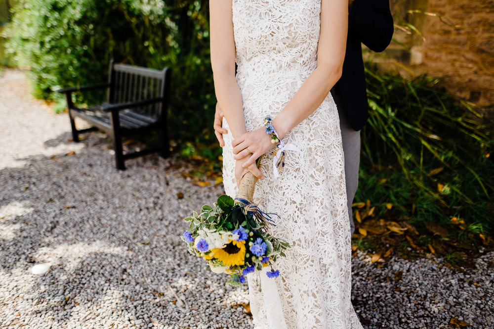 bride in white dress holding blue and yellow flowers