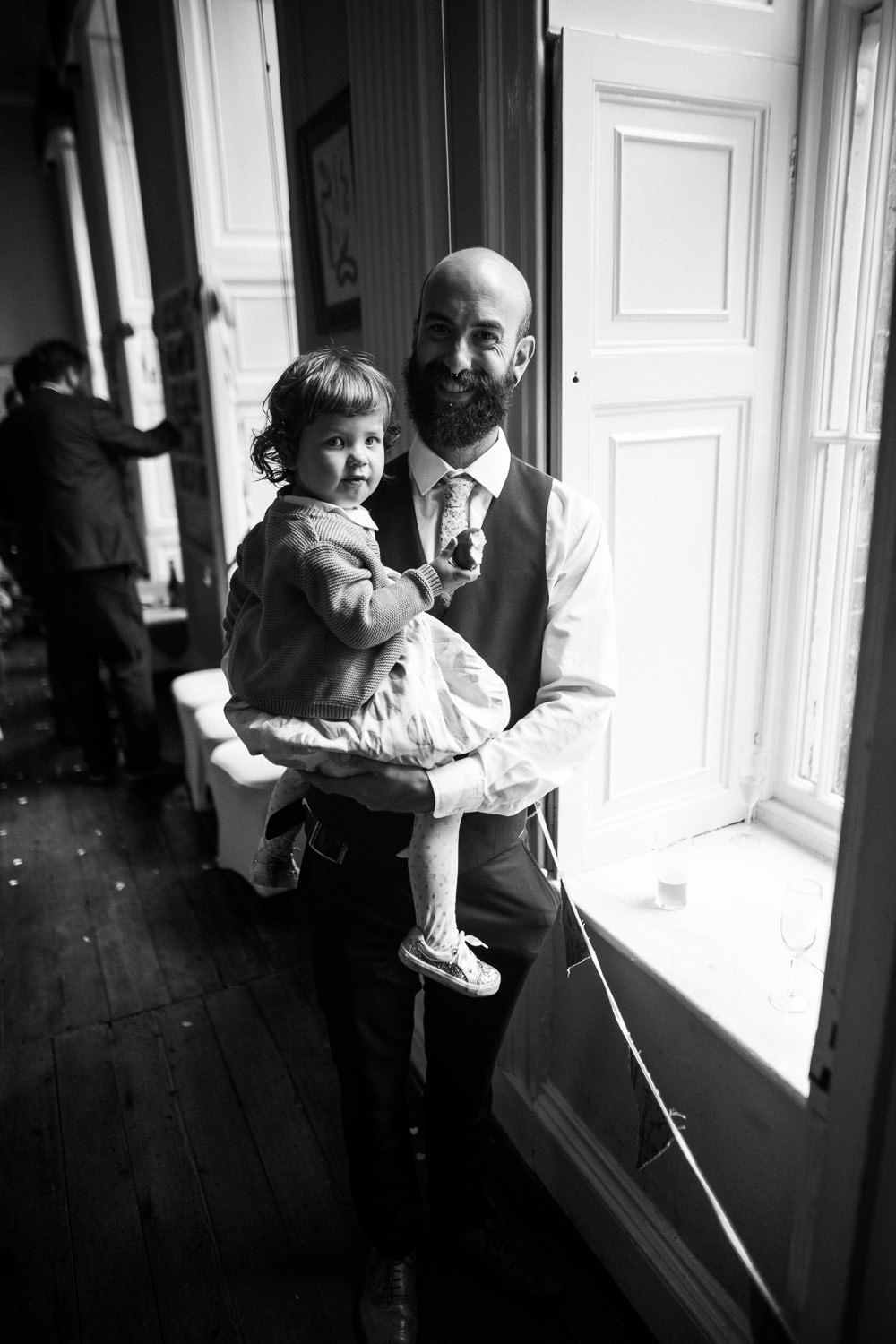 man with beard holding little girl in window light