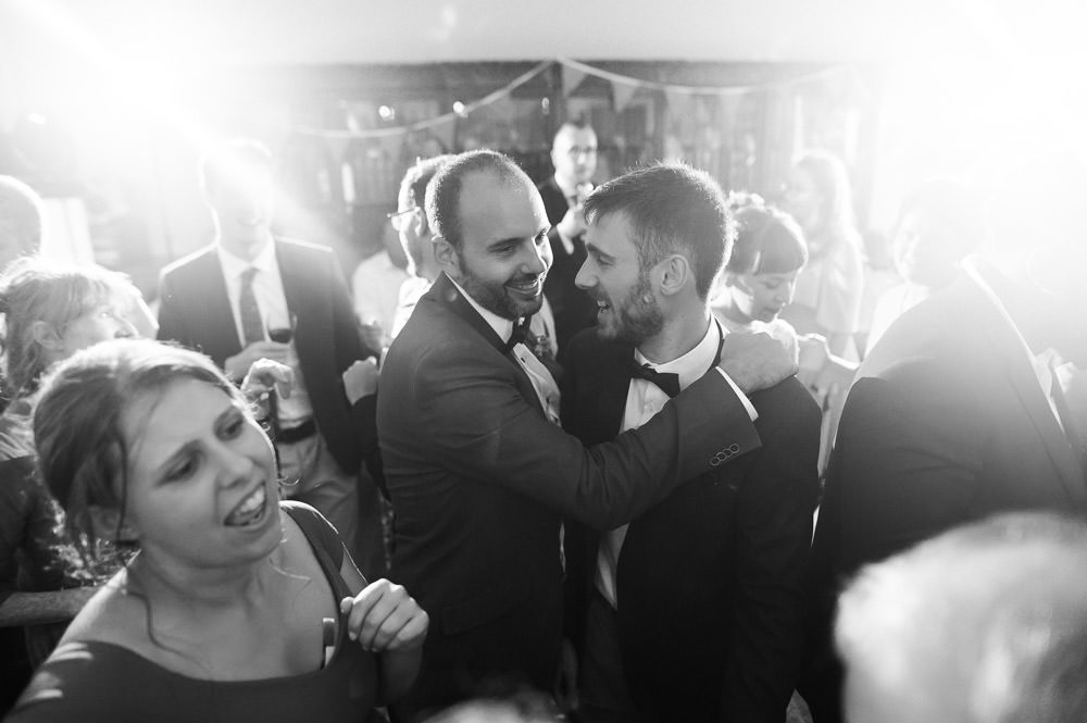 groom and his friend smiling on dance floor