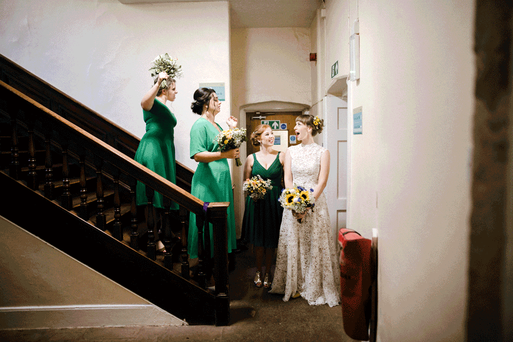 brides maids stood on wooden stair case holding flowers