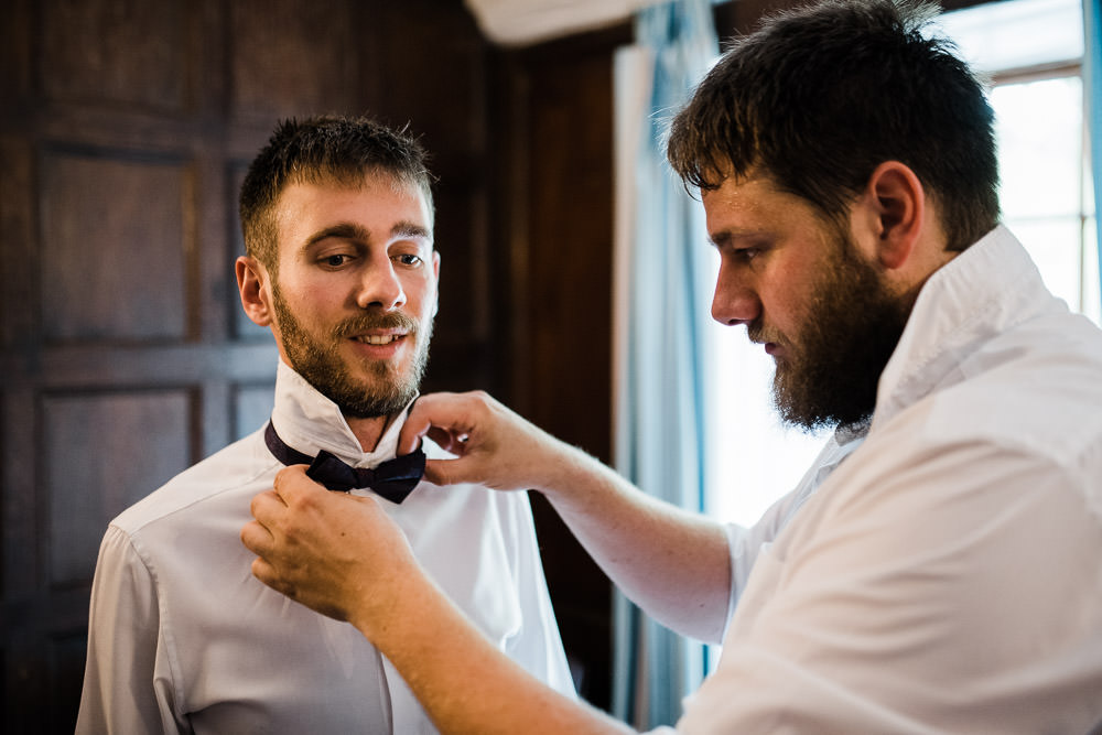 groom putting on a bow tie