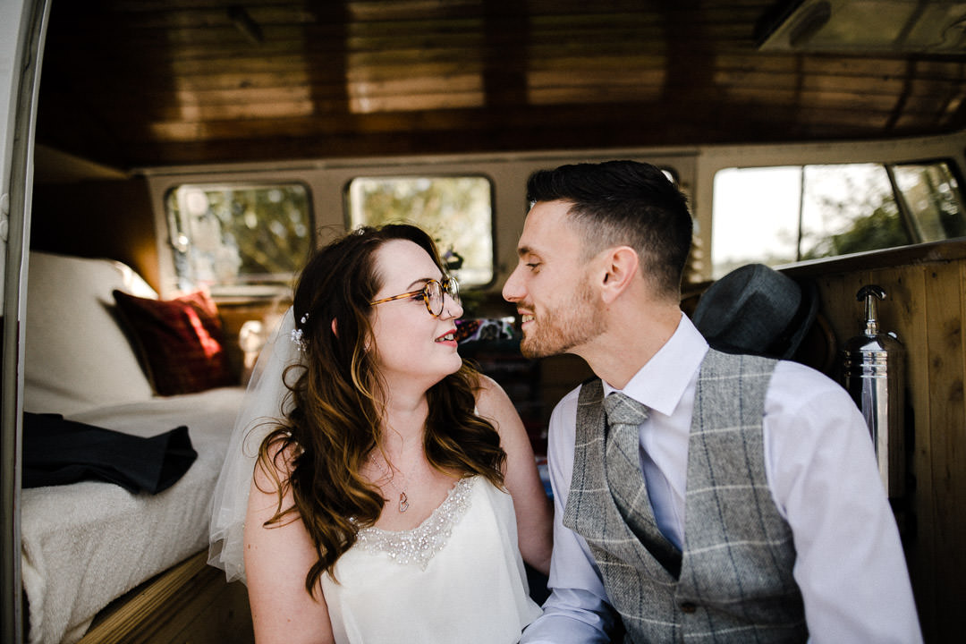 bride and groom sat in camper van kissing