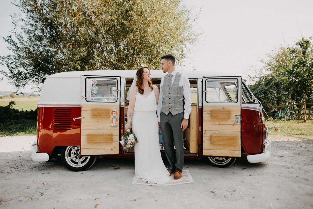 bride and groom standing next to camper van