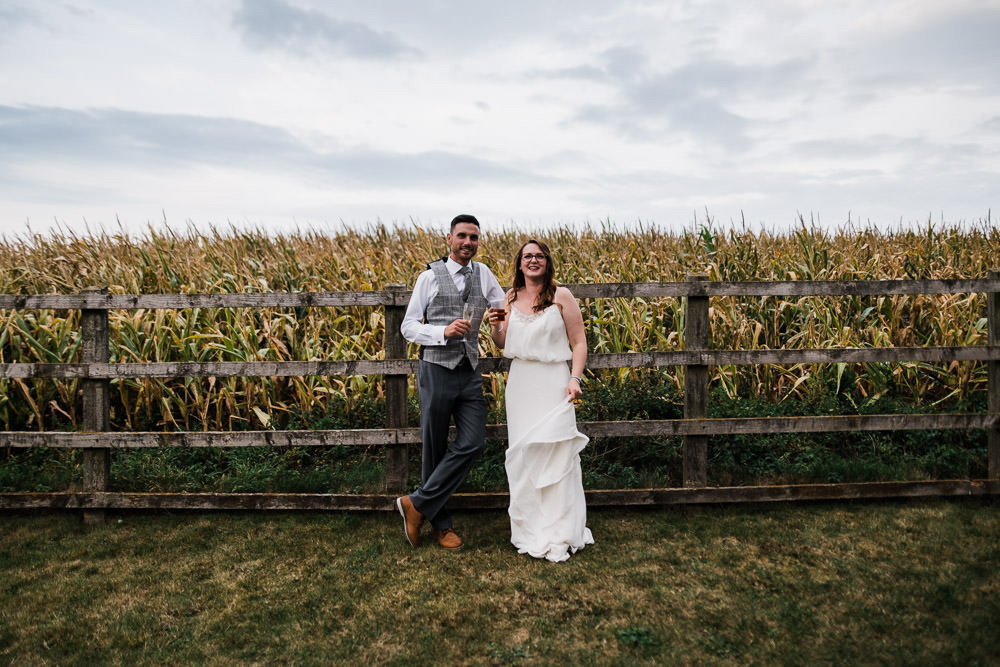 bride and groom stood near wooden fence