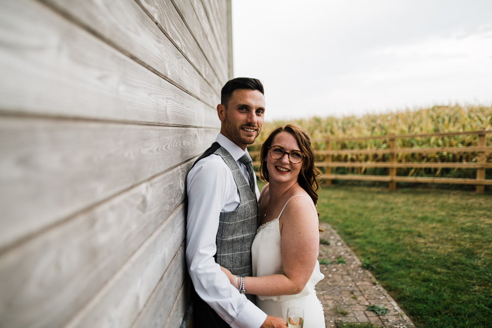wedding couple stood next to wooden wall