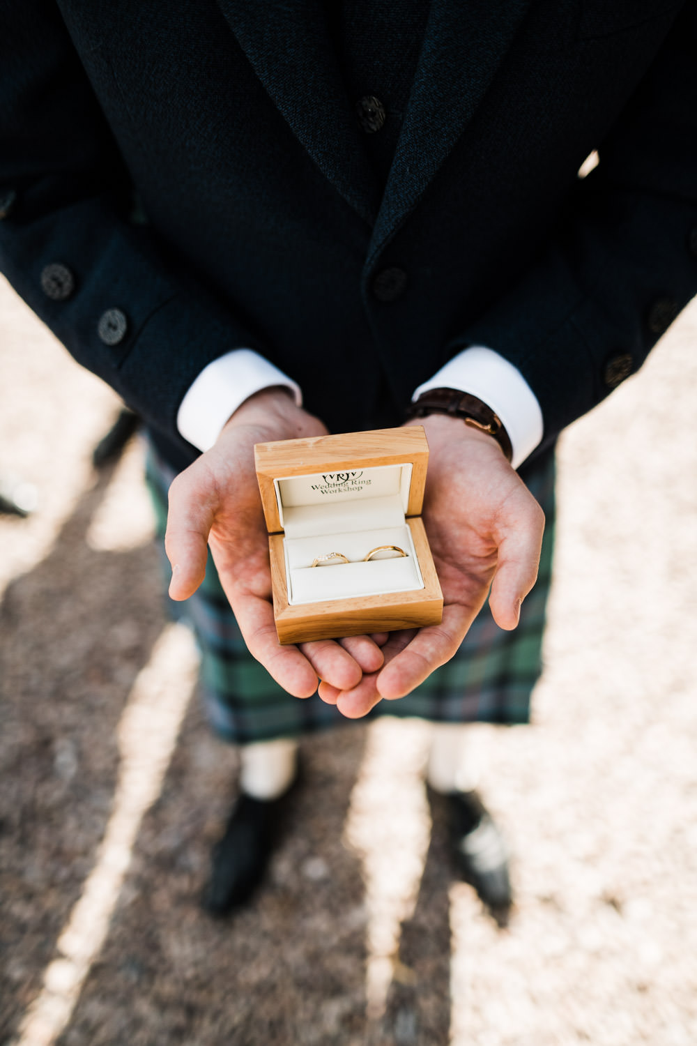 best man holding wedding rings in wooden box