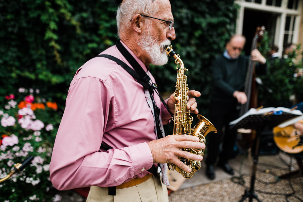 man with grey beard playing saxophone