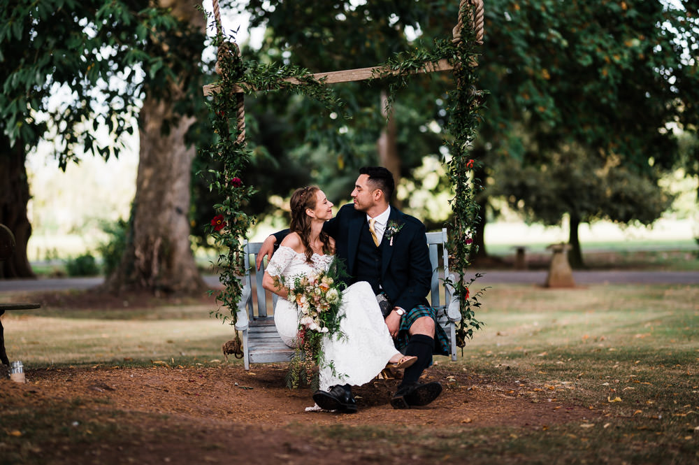 bride and groom sat on a large wooden swing