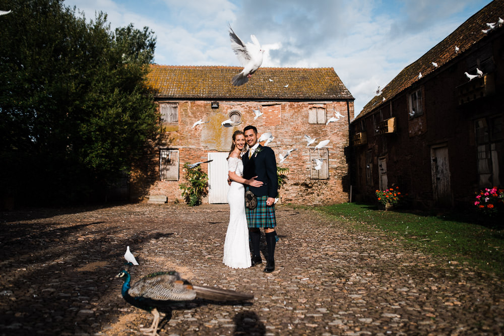 bride and groom with white doves flying around them