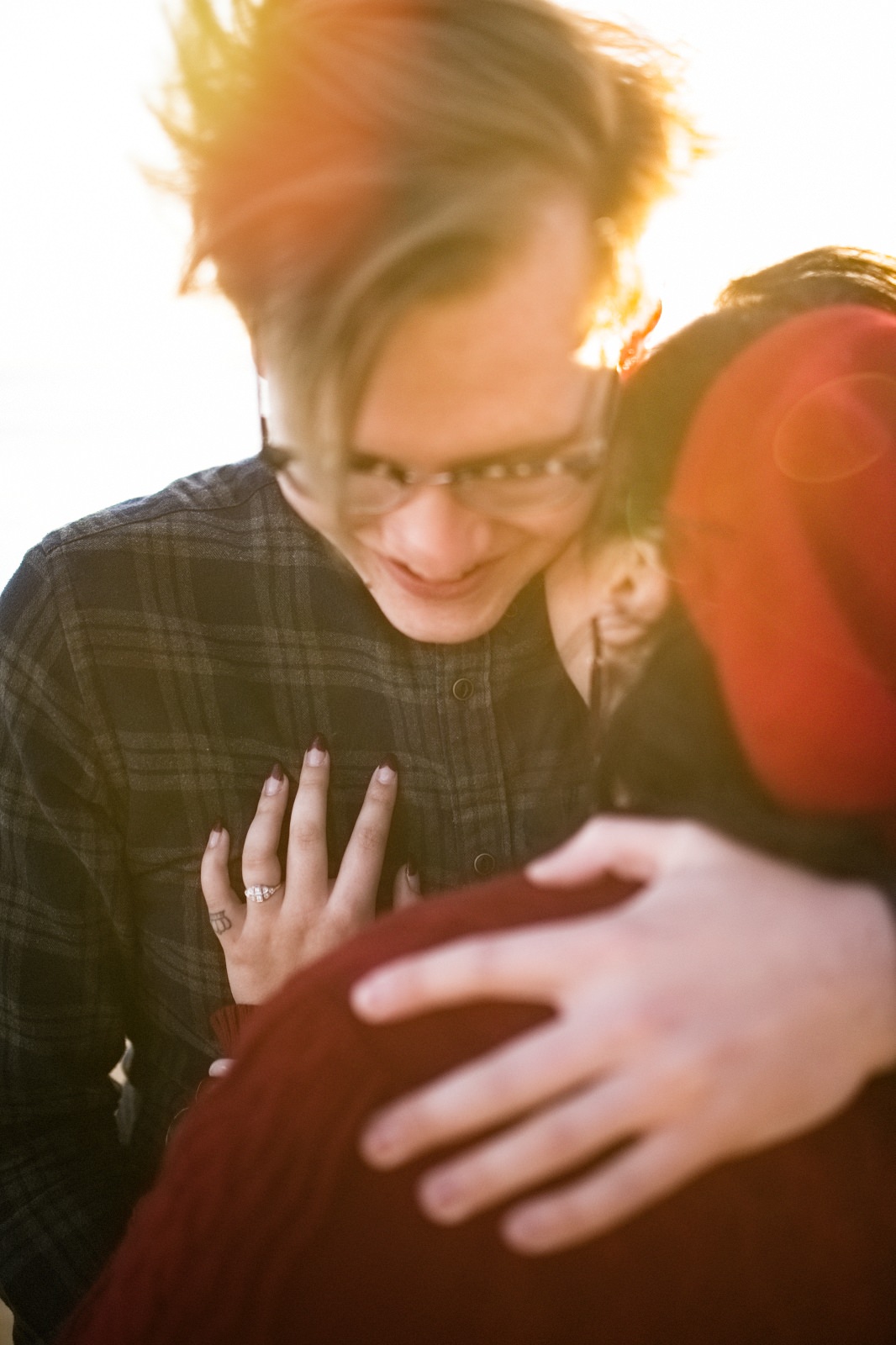 man with glasses on hugging woman with red hat