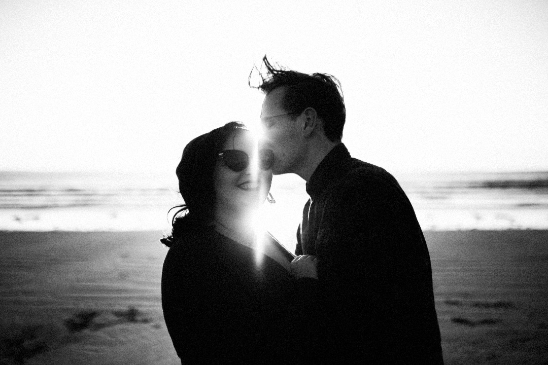 man kissing woman on forehead on beach