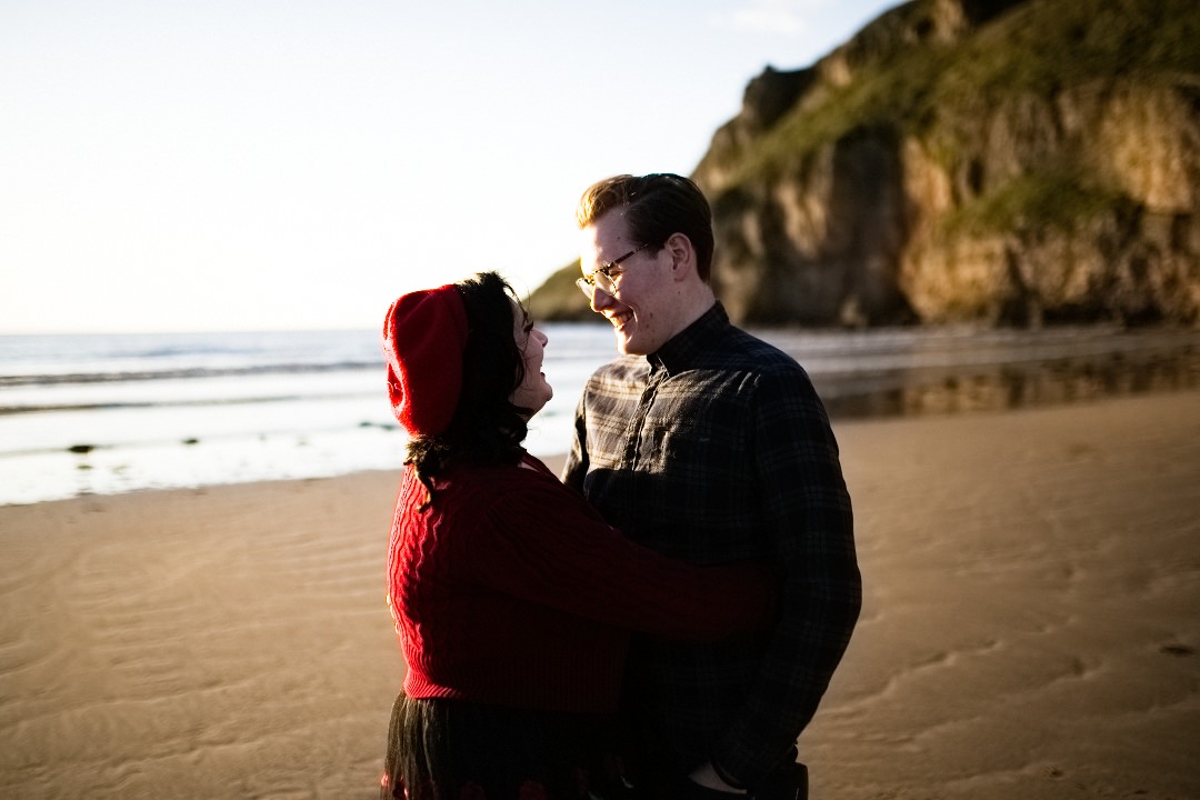 young couple stood on beach smiling