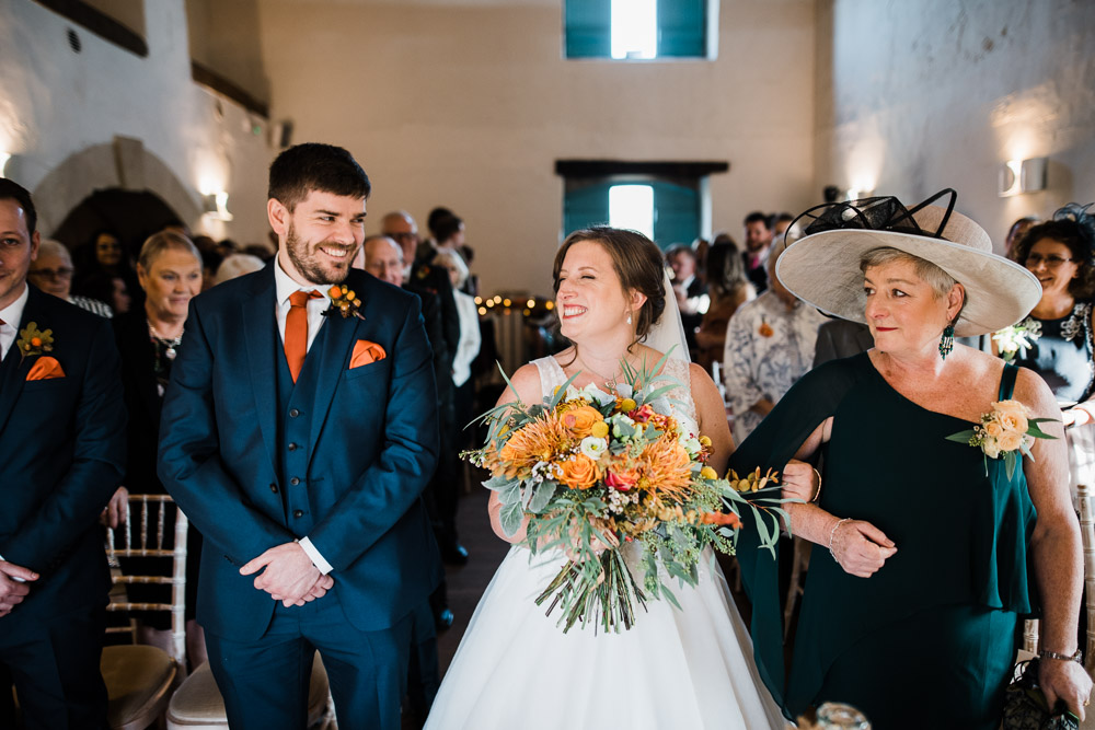 bride and groom smiling at alter with orange flowers