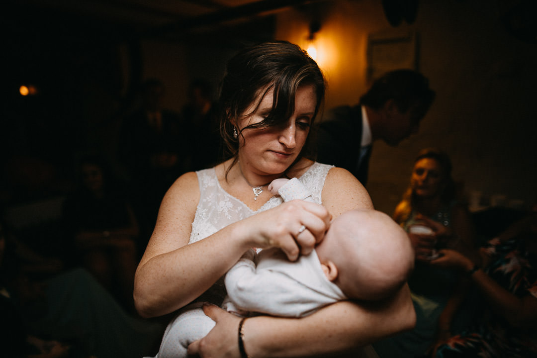 bride in white dress holding a baby