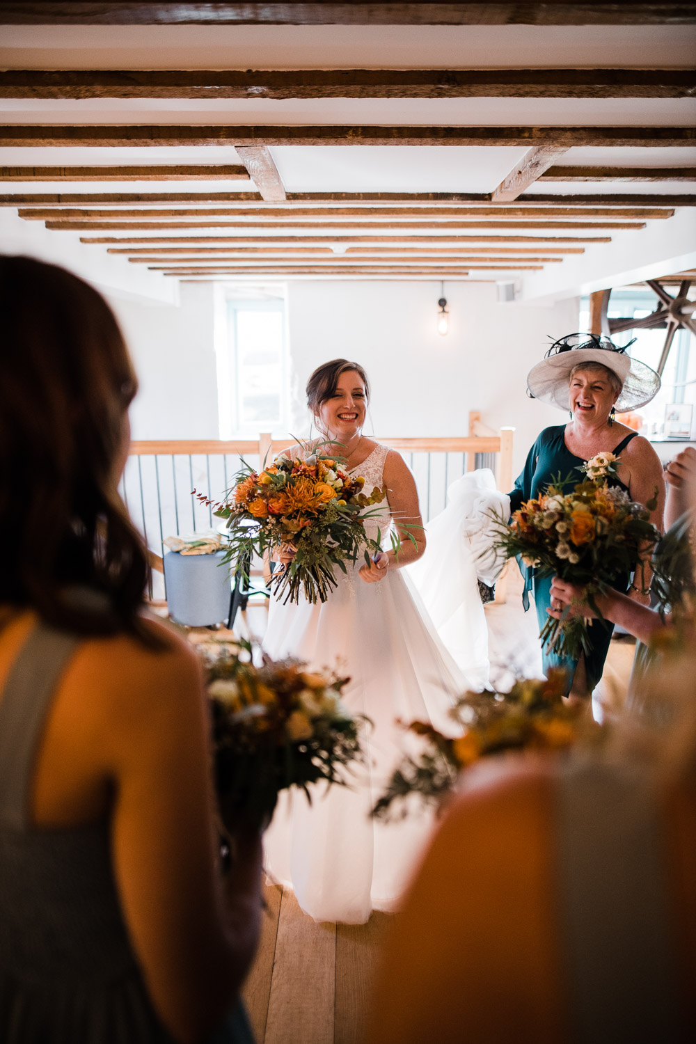 bride holding orange flowers smiling in large room