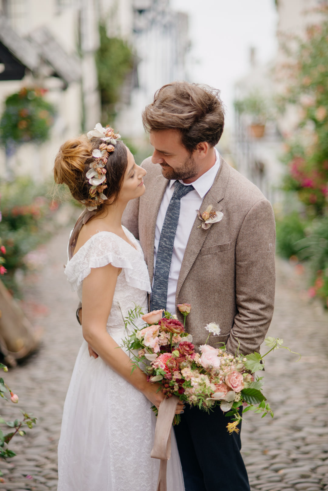 bride and groom stood in cobbled street holding flowers