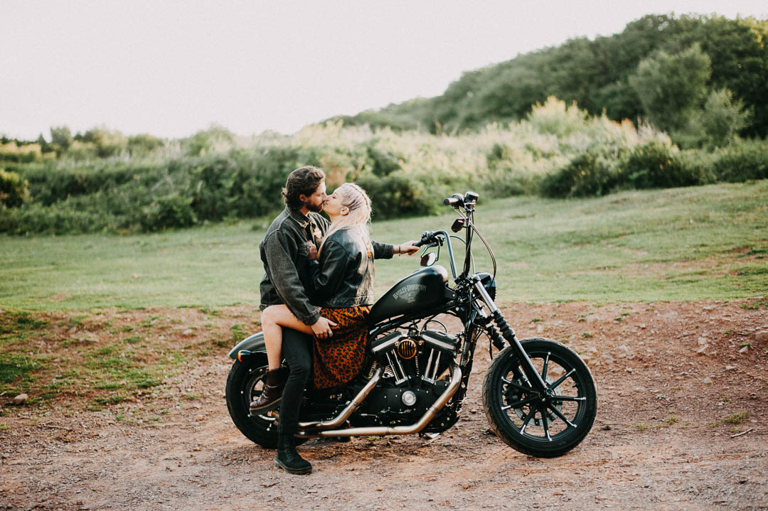 young couple sat on motor bike kissing