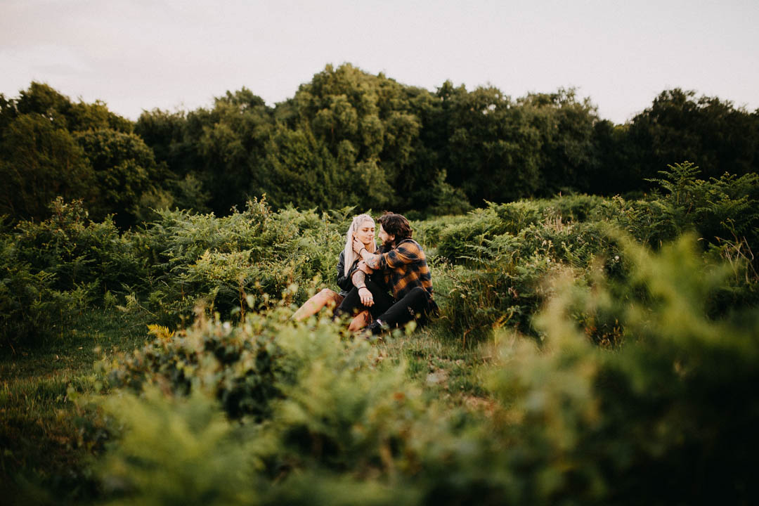 man and woman sat in long grass kissing