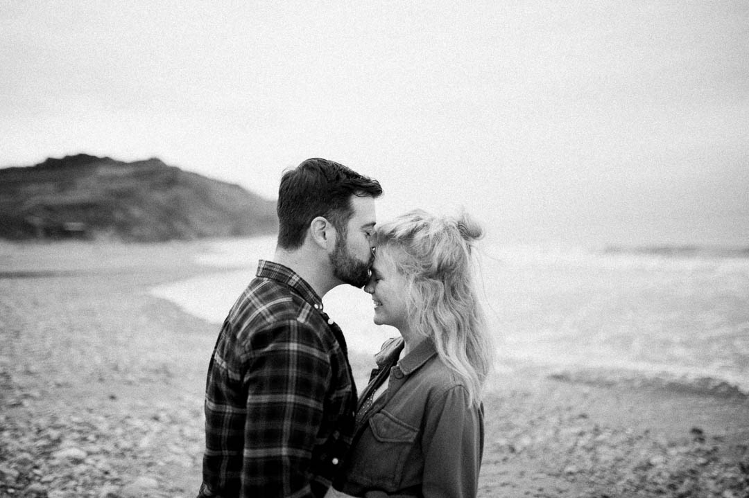 man kissing woman on stormy beach