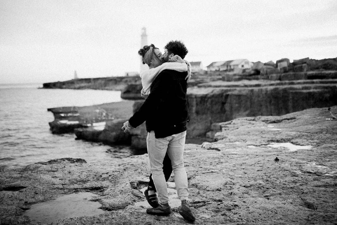 man hugging woman on rugged coastline