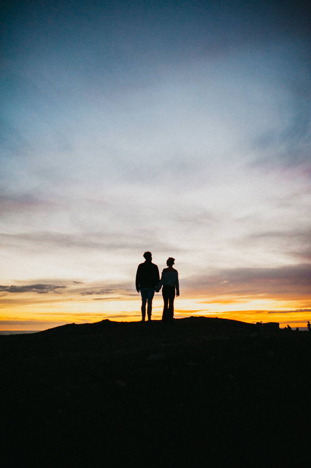 man and woman stood on hill silhouette