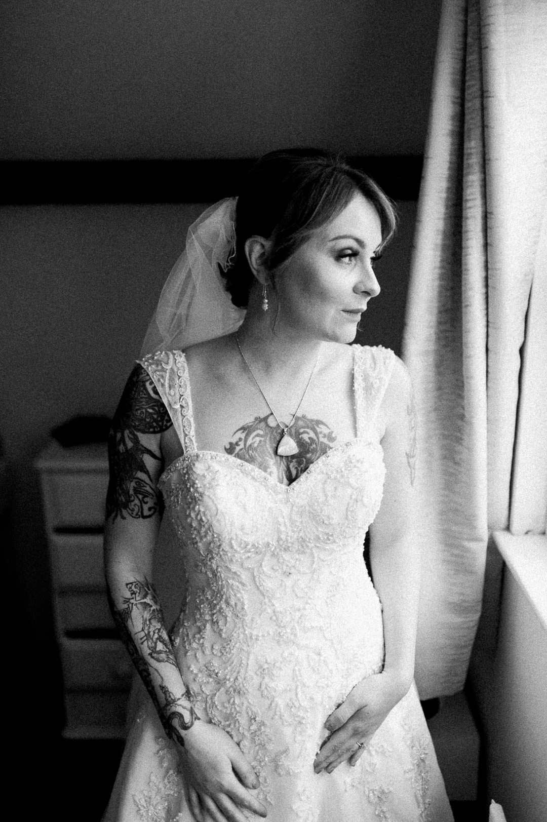 bride with tattoos stood in window light
