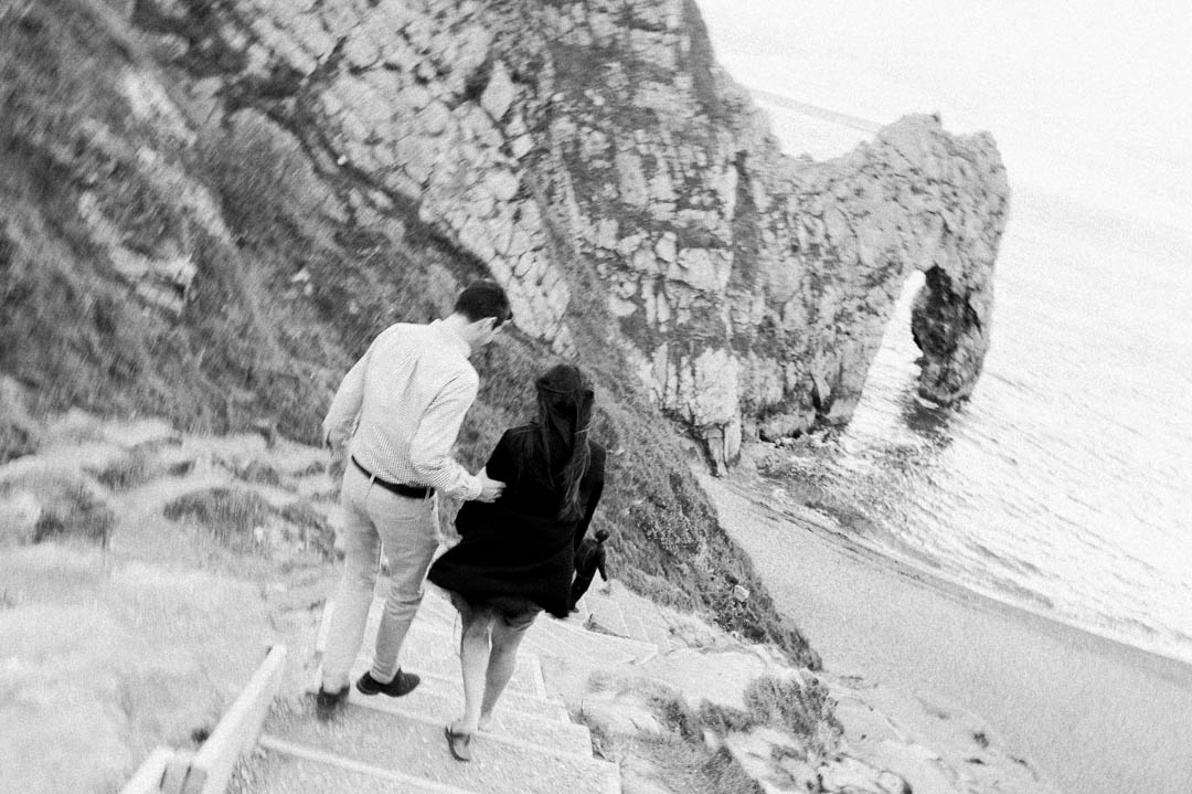 man and woman walking onto windy beach