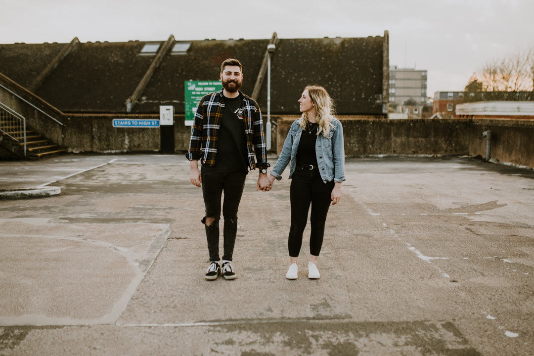 young couple holding hands in car park during day time