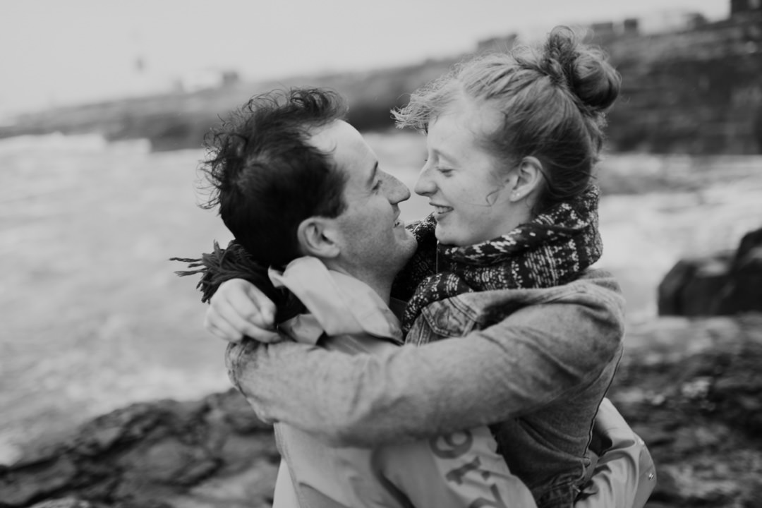 man hugging woman with long hair near sea