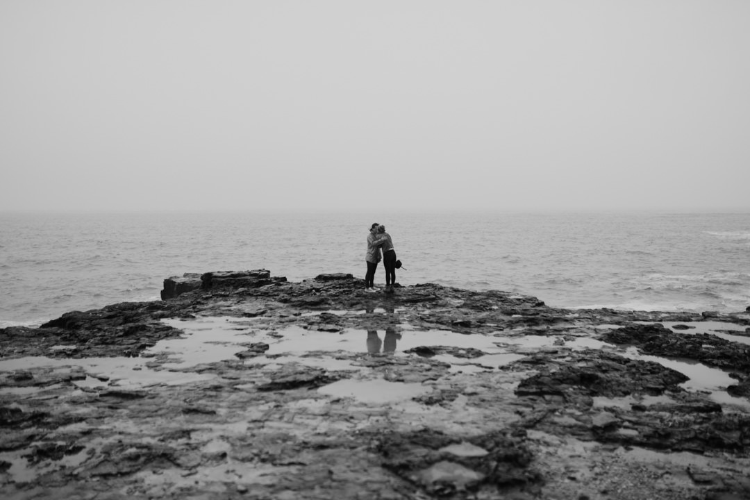 man and woman stood near stormy seas
