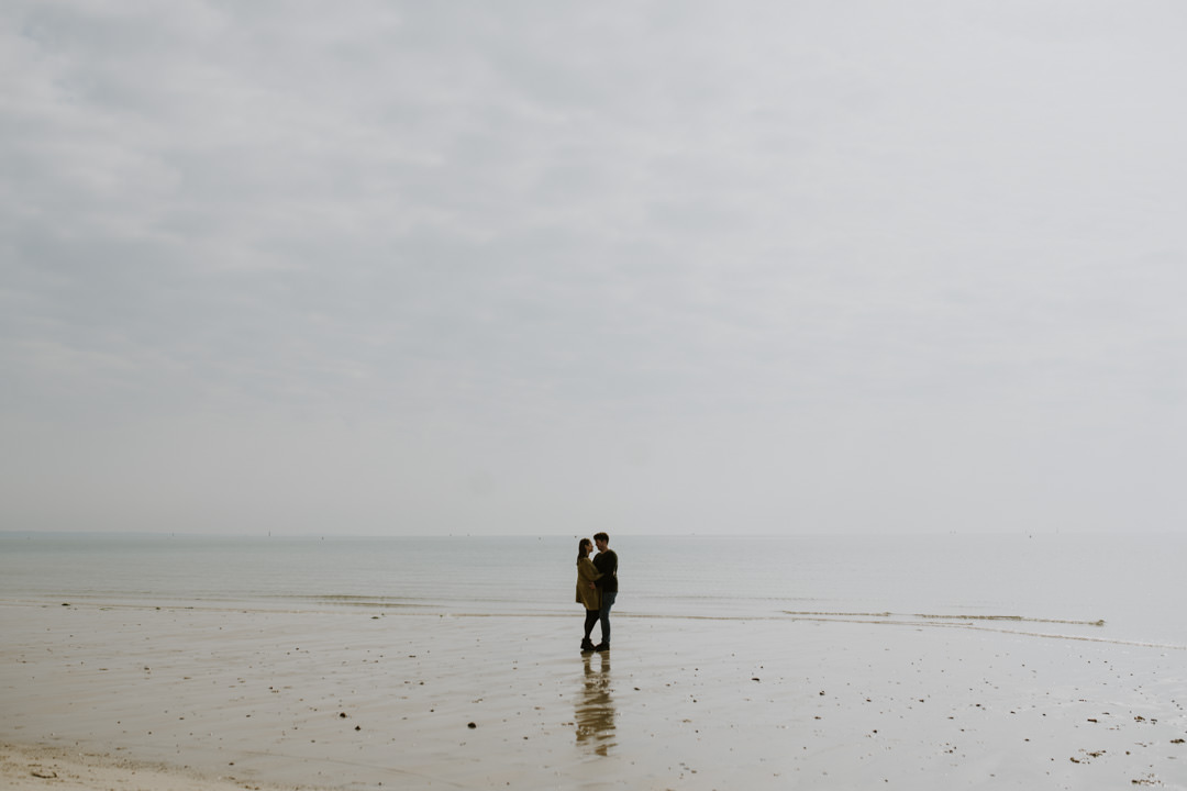 man and woman on beach under grey skies