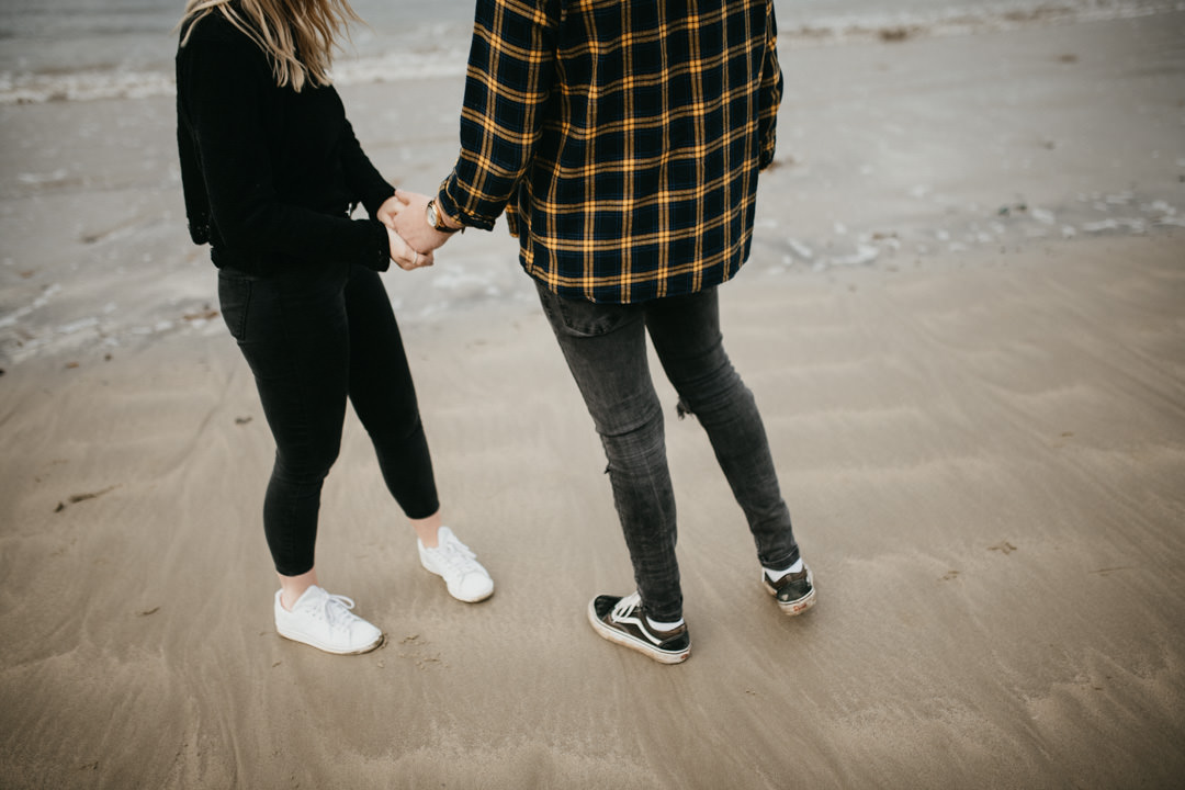 young couple holding hands on sandy beach