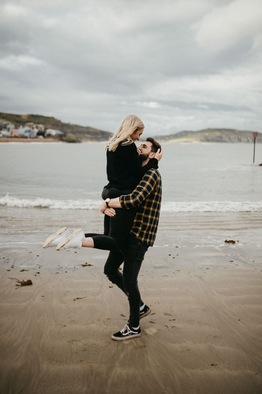 man lifting woman and smiling on beach