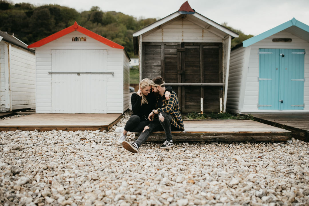 man and woman sat on beach near beach huts