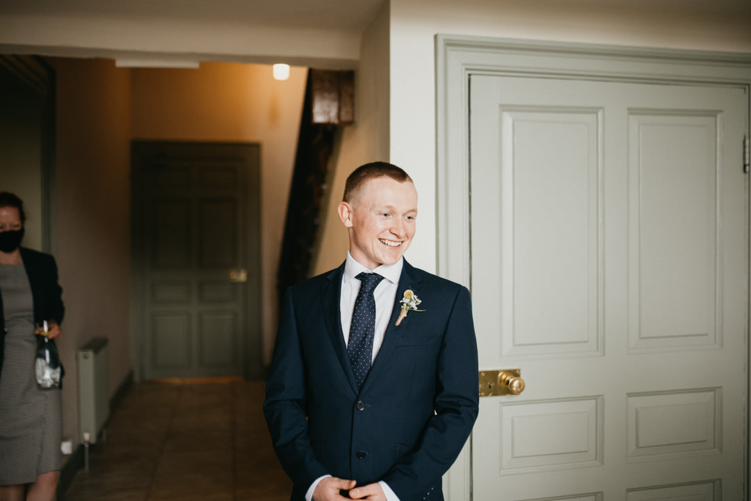 groom in blue suit smiling looking at bride