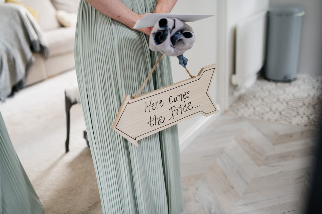 bridesmaid holding wooden sign in house