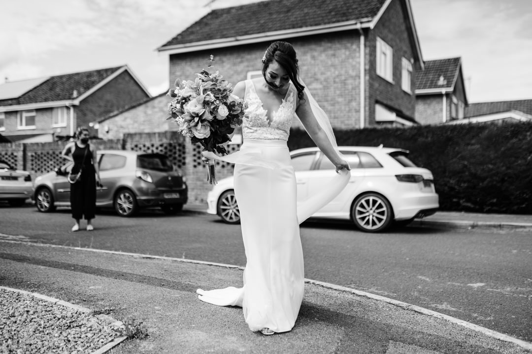 wedding bride stood in street holding white flowers