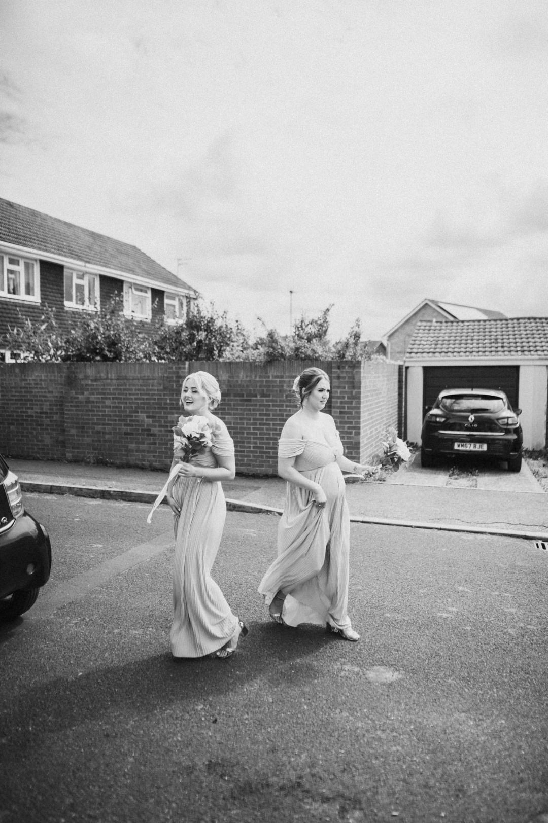 bridesmaids walking in street holding flowers