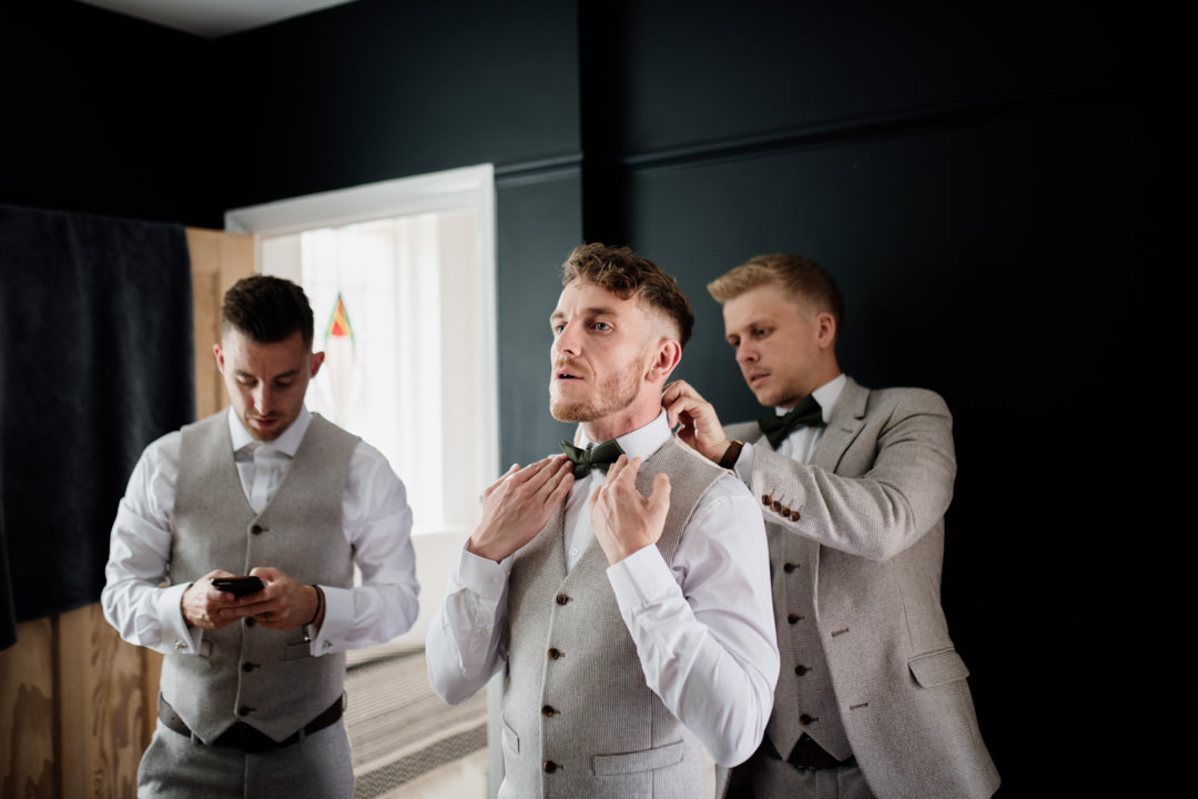 wedding groom putting on suit in house