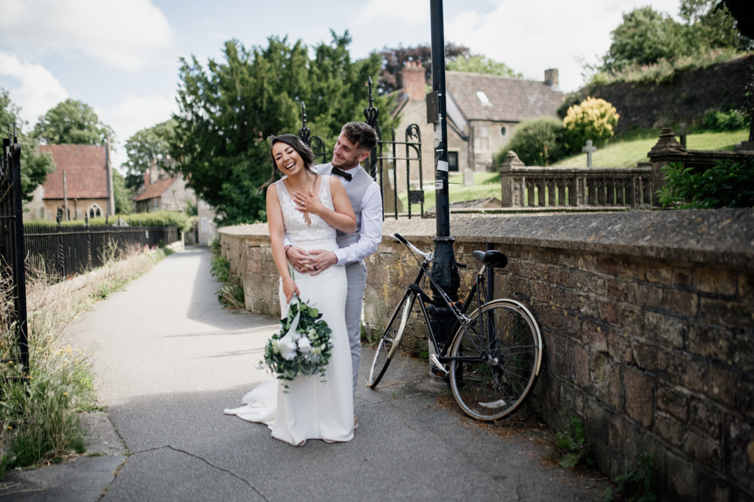 bride and groom stood next to old bicycle in street