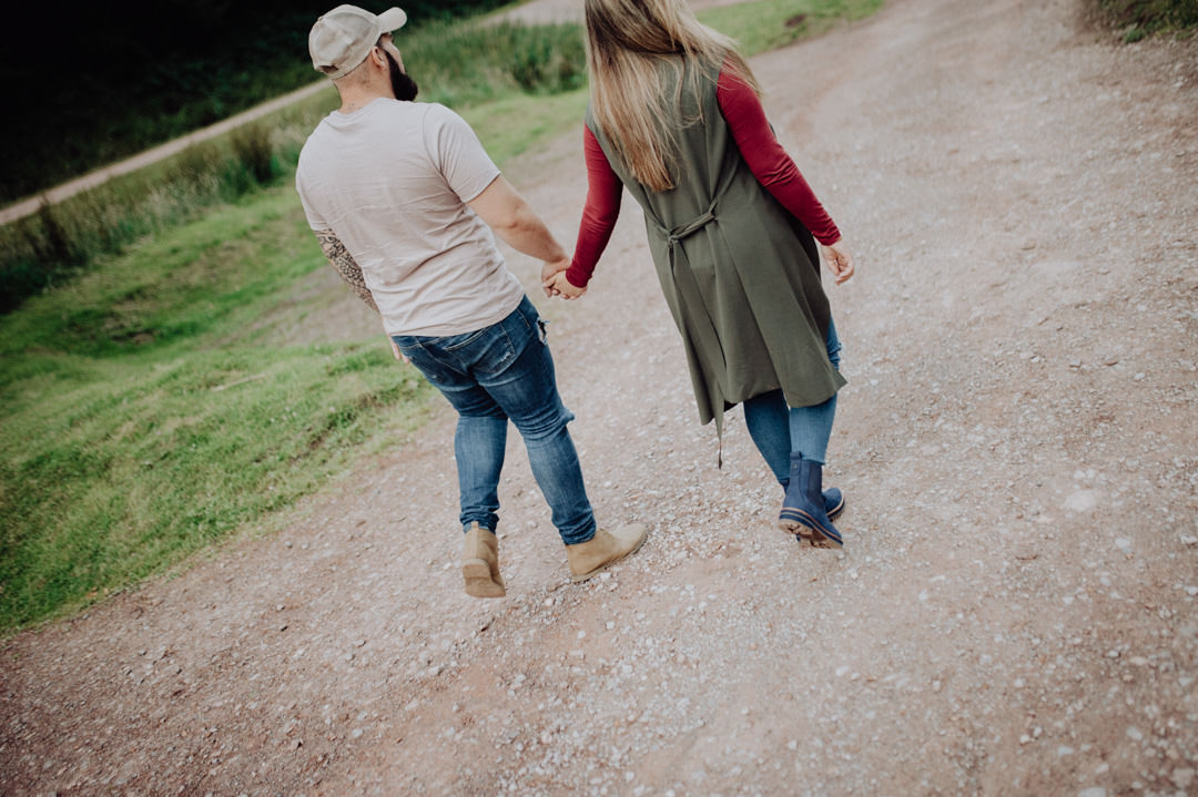 man and woman walking holding hands in woods